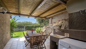 A patio with a table and chairs, a washing machine, and a stone wall.