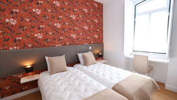 A hotel room with two beds, a window, and a floral wallpaper.