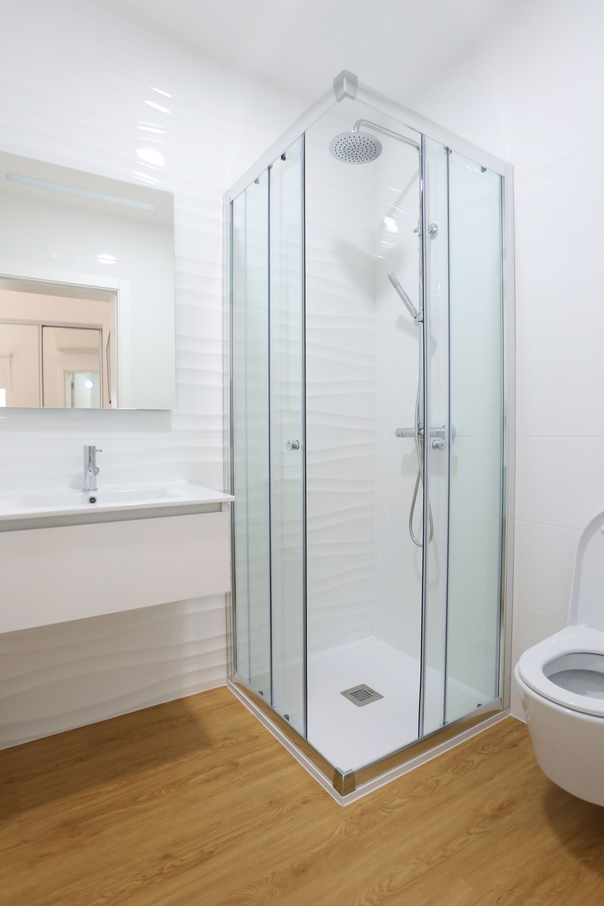 Ein modernes Badezimmer mit einer Duschkabine aus Glas, einem weißen Waschbecken und einer Toilette.