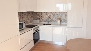 Een moderne keuken met witte kasten, een magnetron, een broodrooster en een spoelbak.