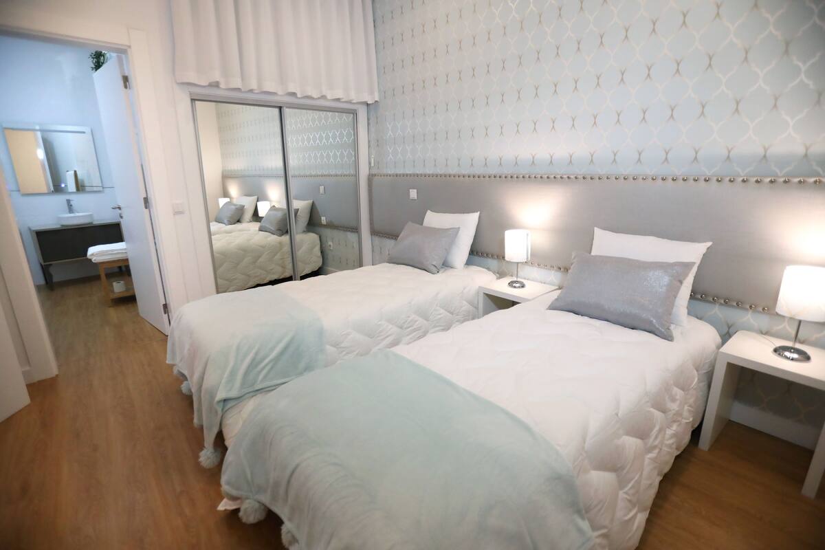Una habitación de hotel con dos camas, un baño y un espejo.