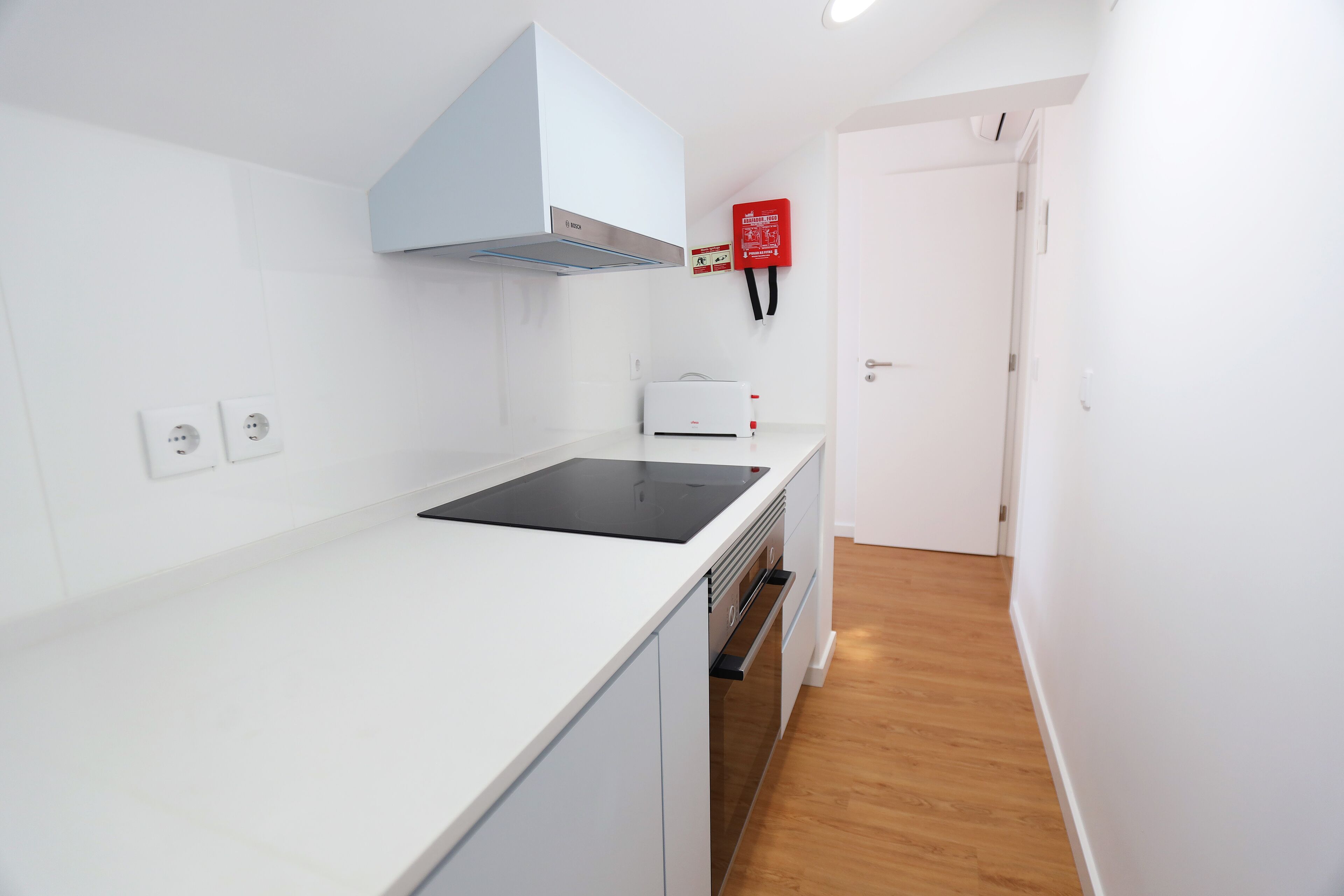 A modern kitchen with white cabinetry, a built-in stove, and a white countertop.