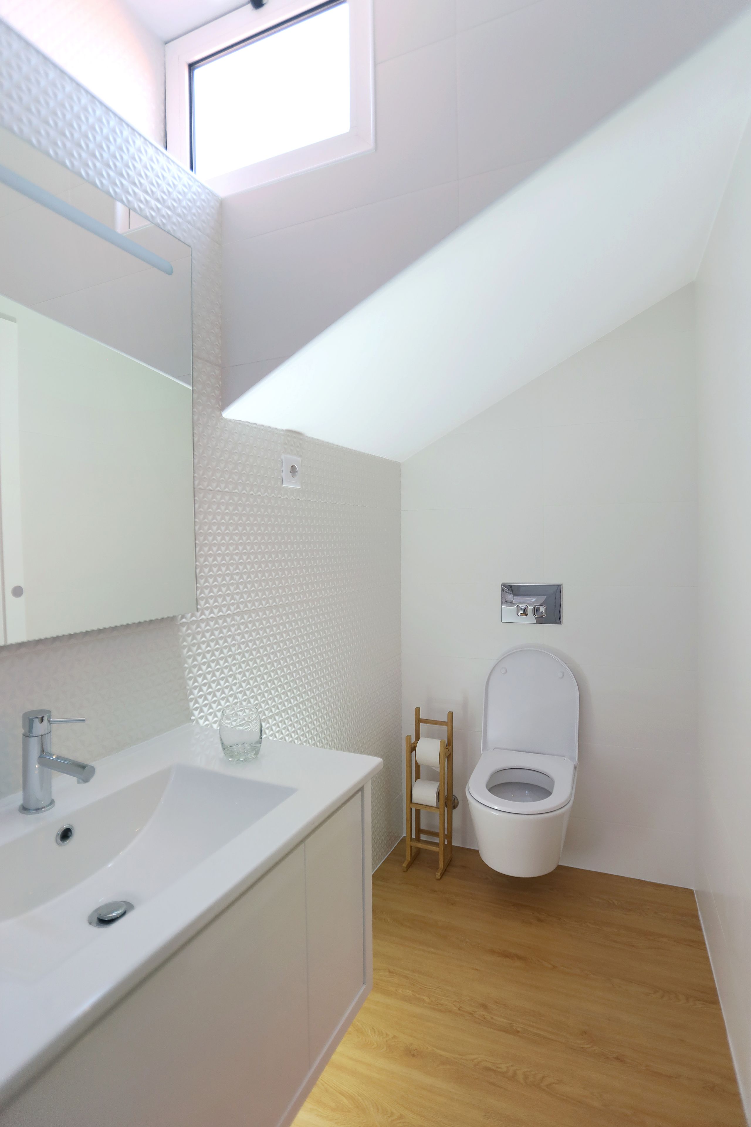 Un bany modern amb un lavabo, mirall i vàter blancs.
