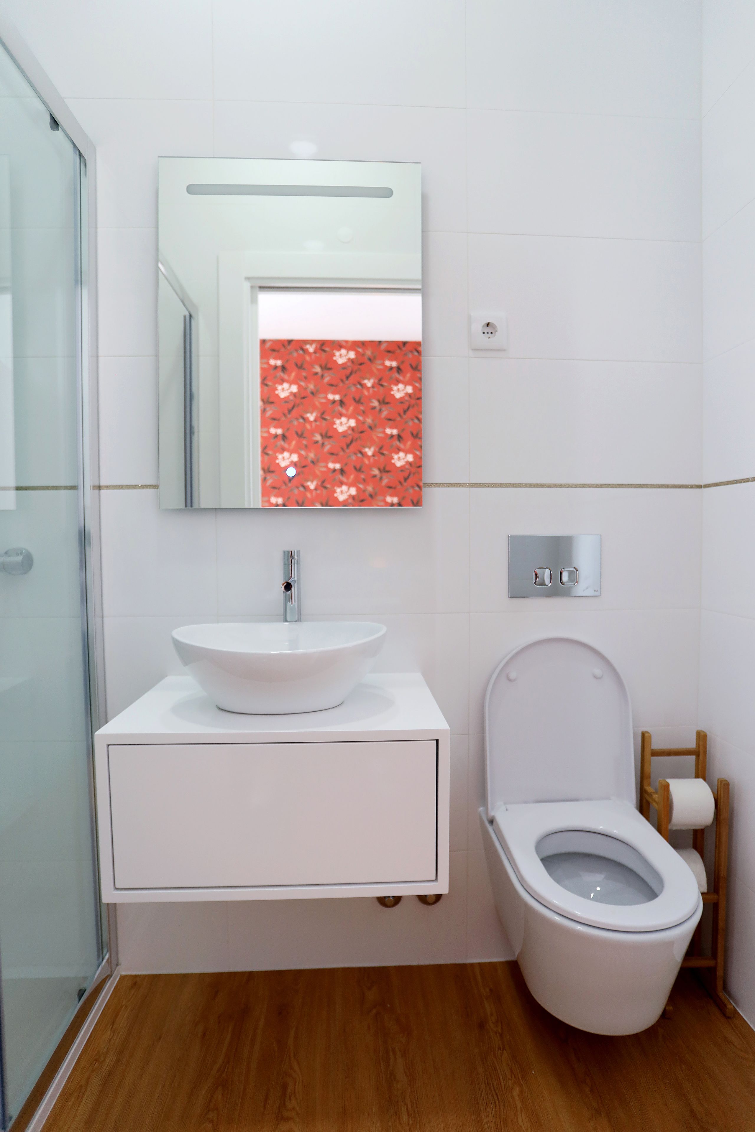A bathroom with a white sink, a mirror, and a toilet.