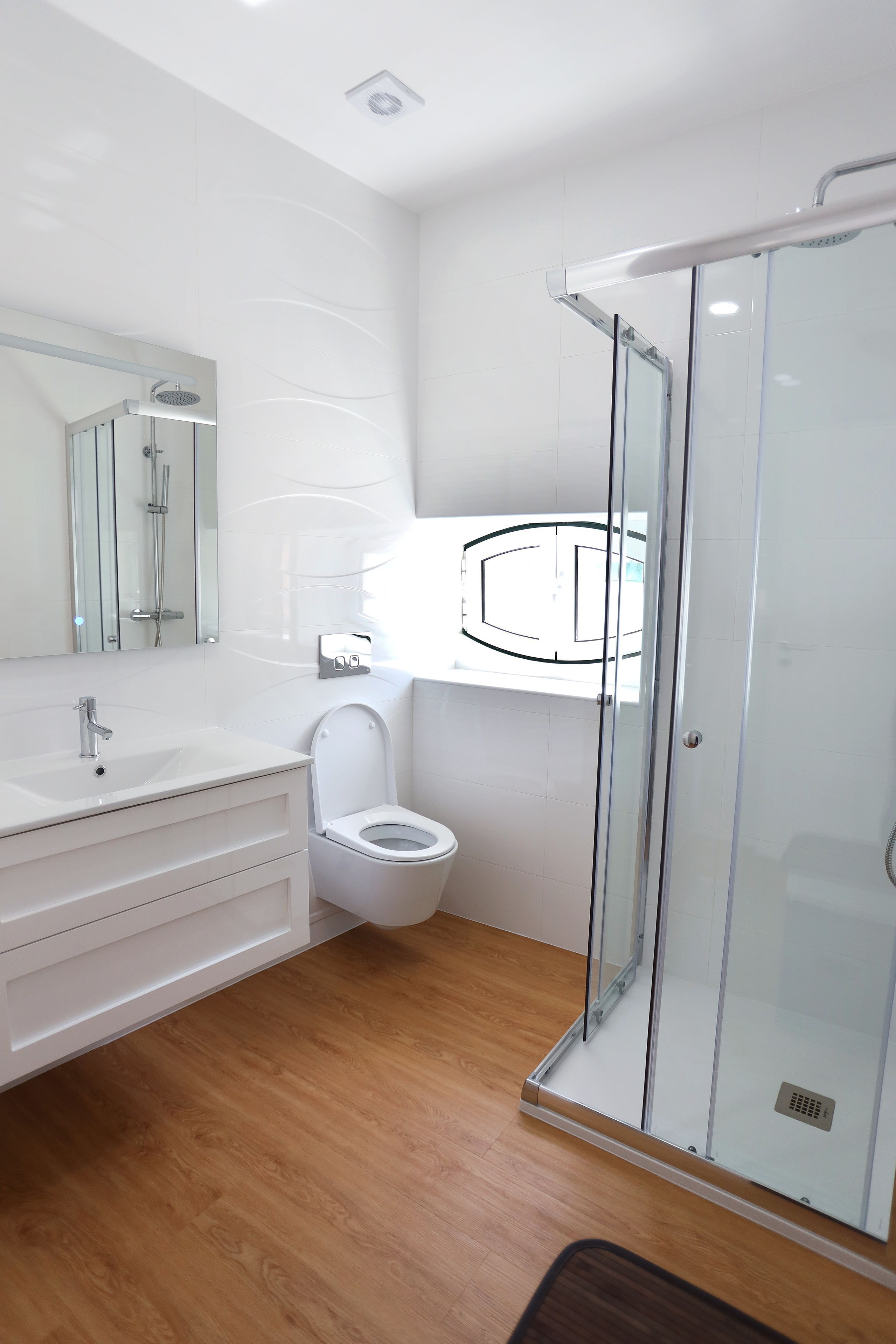 A modern bathroom with a glass-enclosed shower, a white sink, and a toilet.
