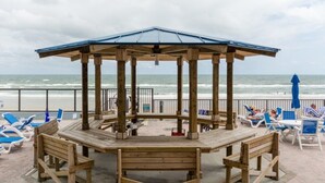 A wooden gazebo with a blue roof overlooking the beach.