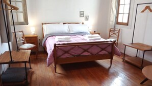 A neatly arranged bedroom with a wooden bed, bedside tables, a chair, and a hanging rack. - Spacious illuminated and unique apartment (Montevideo)