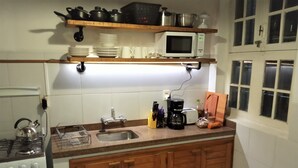 A kitchen with a stove, microwave, sink, and wooden cabinets. - Spacious illuminated and unique apartment (Montevideo)