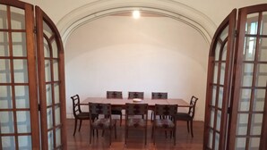 A dining room with a wooden table and chairs, surrounded by glass doors. - Spacious illuminated and unique apartment (Montevideo)