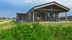 A modern building with a covered patio area, a bicycle, and a grassy foreground with flowers.