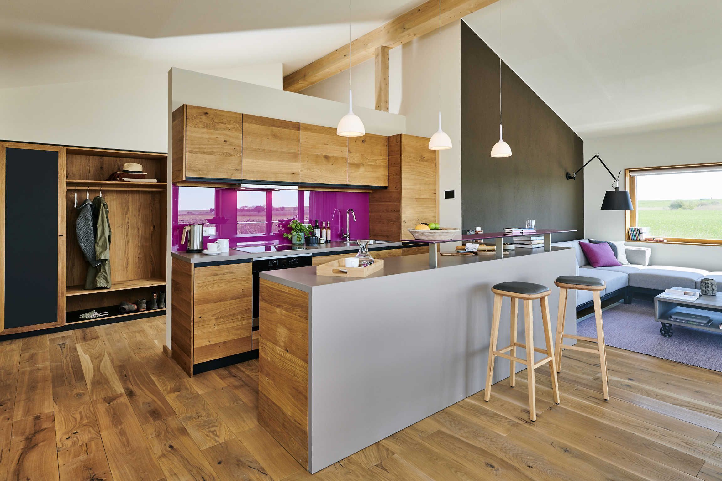 A modern kitchen with wooden cabinets, a central island, bar stools, and pendant lighting.