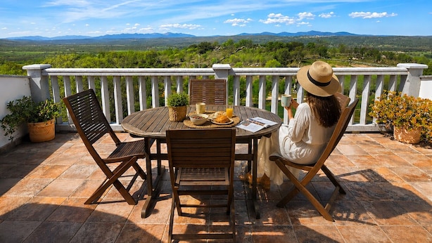 A terrace with a table and chairs, a potted plant, and a view of the landscape. - Panoramic Terrace, Sunsets, Nature and Stargazing in the Sierra de Béjar (Navalmoral)