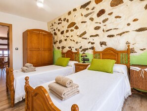A hotel room with two beds, wooden headboards, a stone wall, and a wooden wardrobe. - Panoramic Terrace, Sunsets, Nature and Stargazing in the Sierra de Béjar (Navalmoral)