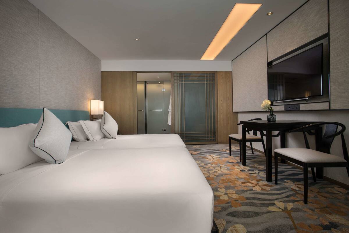 Ein Hotelzimmer mit einem großen Bett, einem Schreibtisch und einem Fernseher.