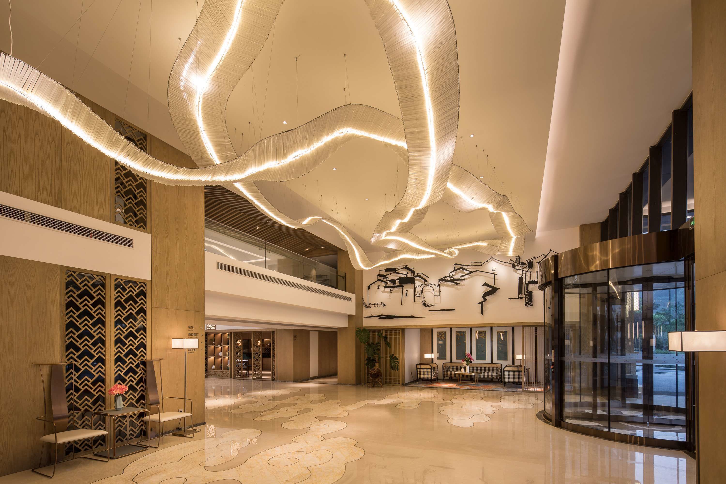 A spacious lobby with a high ceiling, modern lighting fixtures, and a large seating area.