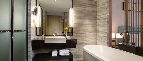 A modern bathroom with a freestanding bathtub, a large mirror, and a dark wooden vanity.