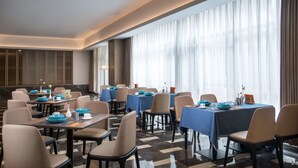 A hotel dining area with tables set for meals, large windows with sheer curtains, and a modern interior design. - Ramada by Wyndham Zhenjiang City Center (Zhenjiang)