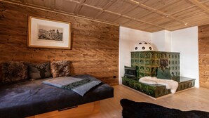 Una habitación con techo de madera, un cuadro en la pared, un sofá con una manta de piel y un mueble verde con un objeto blanco encima.
