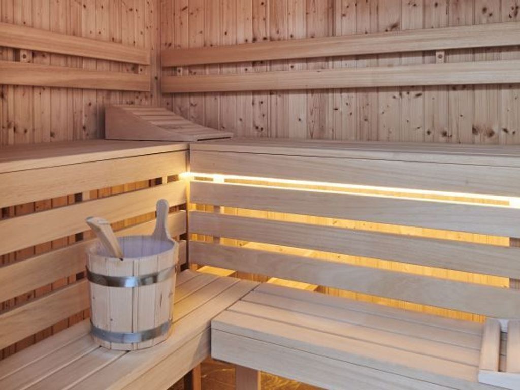 Una sauna de madera con bancos y un cubo.