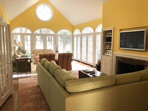 Cozy living area with a fireplace, sofa, armchairs, and TV.