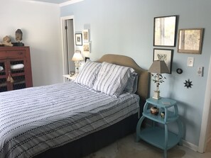 A bedroom with a bed, a nightstand, a dresser, and wall decorations. - Enjoy this comfy 3 bedroom home & walk, bike or take the trolley to the beach! (Bethany Beach)