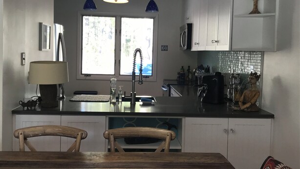 Una cocina moderna con una isla central, muebles blancos y un ventanal amplio.