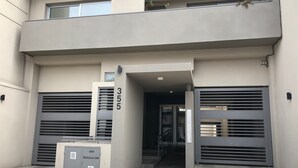 A modern building entrance with a number 355 sign, a gas regulation box, and a staircase leading to an upper level. - Calido y Luminoso Studio en Salta (Salta)