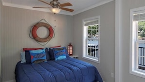 A bedroom with a bed, a ceiling fan, a window, and a lifebuoy on the wall. - Single level home in a gentle, quiet , deep water cove  at Lake of the Ozarks . (Roach)