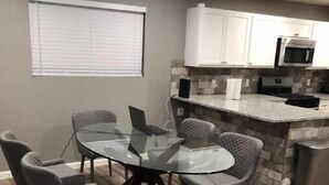 Una cocina moderna con armarios blancos, microondas integrado y encimera de granito.