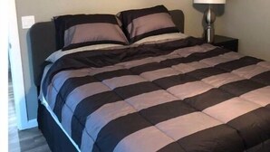 Un dormitorio con una cama, una mesita de noche, una lámpara y un ventilador de techo.