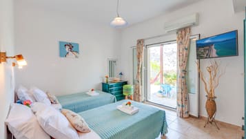 Ein Zimmer mit zwei Betten, einem Fernseher und Blick ins Freie.