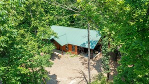 A cabin surrounded by dense forest with a gravel driveway leading to a wooden deck. - The Blue Heron, HIDDEN IN THE WOODS YET CLOSE TO TOWN (Broken Bow)