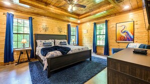 A wooden cabin bedroom with a bed, a desk, and a ceiling fan. - The Blue Heron, HIDDEN IN THE WOODS YET CLOSE TO TOWN (Broken Bow)