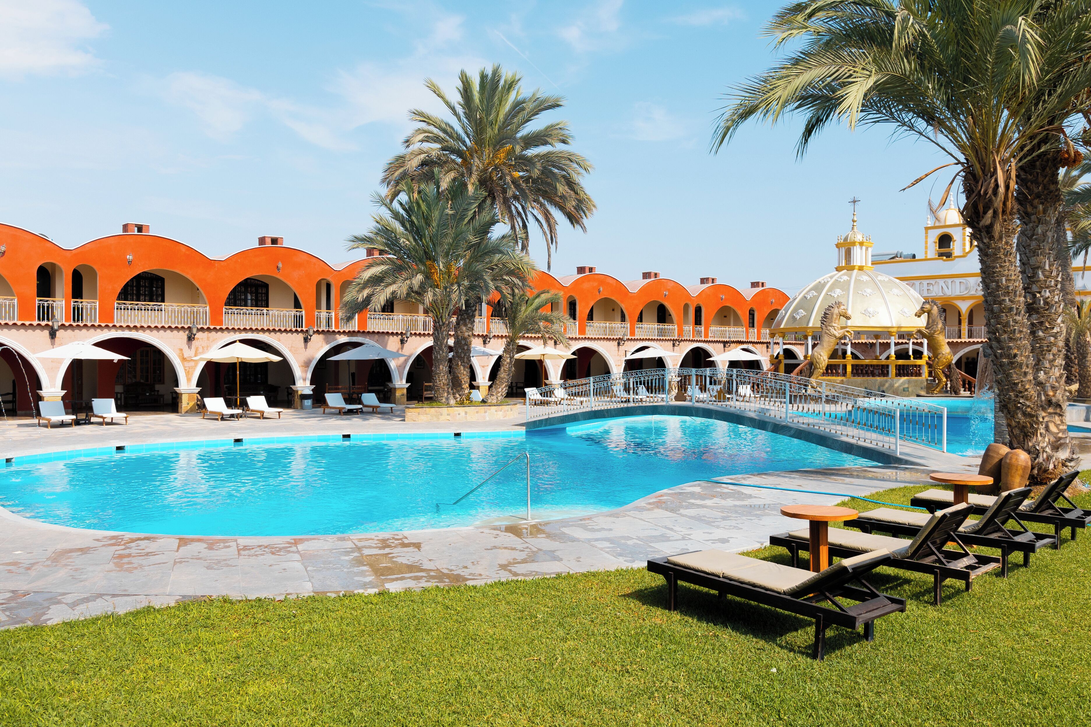 A swimming pool with lounge chairs and palm trees.