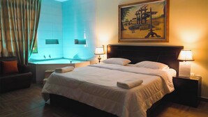 Hotelkamer met een bed, twee bedlampen, een schilderij, een raam met gordijnen en een bad.
