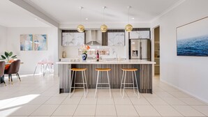 A modern kitchen with a large island, bar stools, and pendant lighting. - Lakefront villa with a spacious panoramic balcony in Sanctuary Lakes (Point Cook)