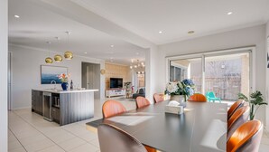 A modern kitchen with a dining area, featuring a large island, stainless steel appliances, and a view to the outside. - Lakefront villa with a spacious panoramic balcony in Sanctuary Lakes (Point Cook)