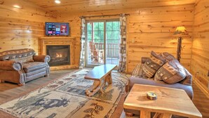 A cozy cabin interior with a fireplace, wooden furniture, and a television. - Cozy Lodge Suite with Kitchen in Amish Country (Millersburg)