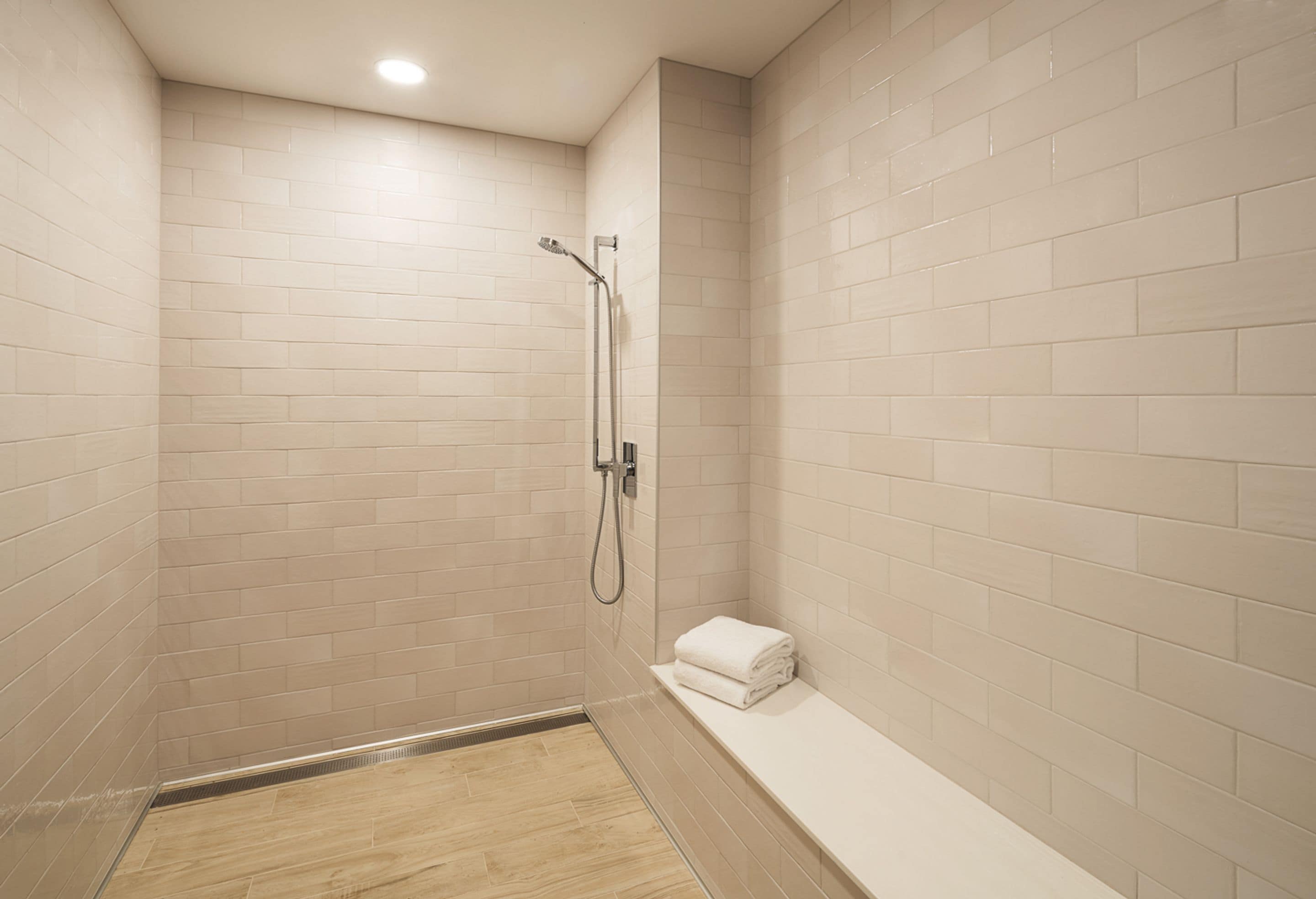 Un pequeño espacio de ducha con azulejos, un banco y un perchero para toallas.