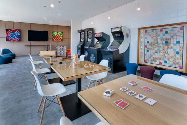 A modern gaming area with a large Scrabble board, multiple gaming machines, and a flat-screen TV.