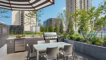 Un patio exterior con una parrilla, una mesa de comedor y sillas.