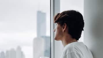 A person standing by a window with a cityscape view.