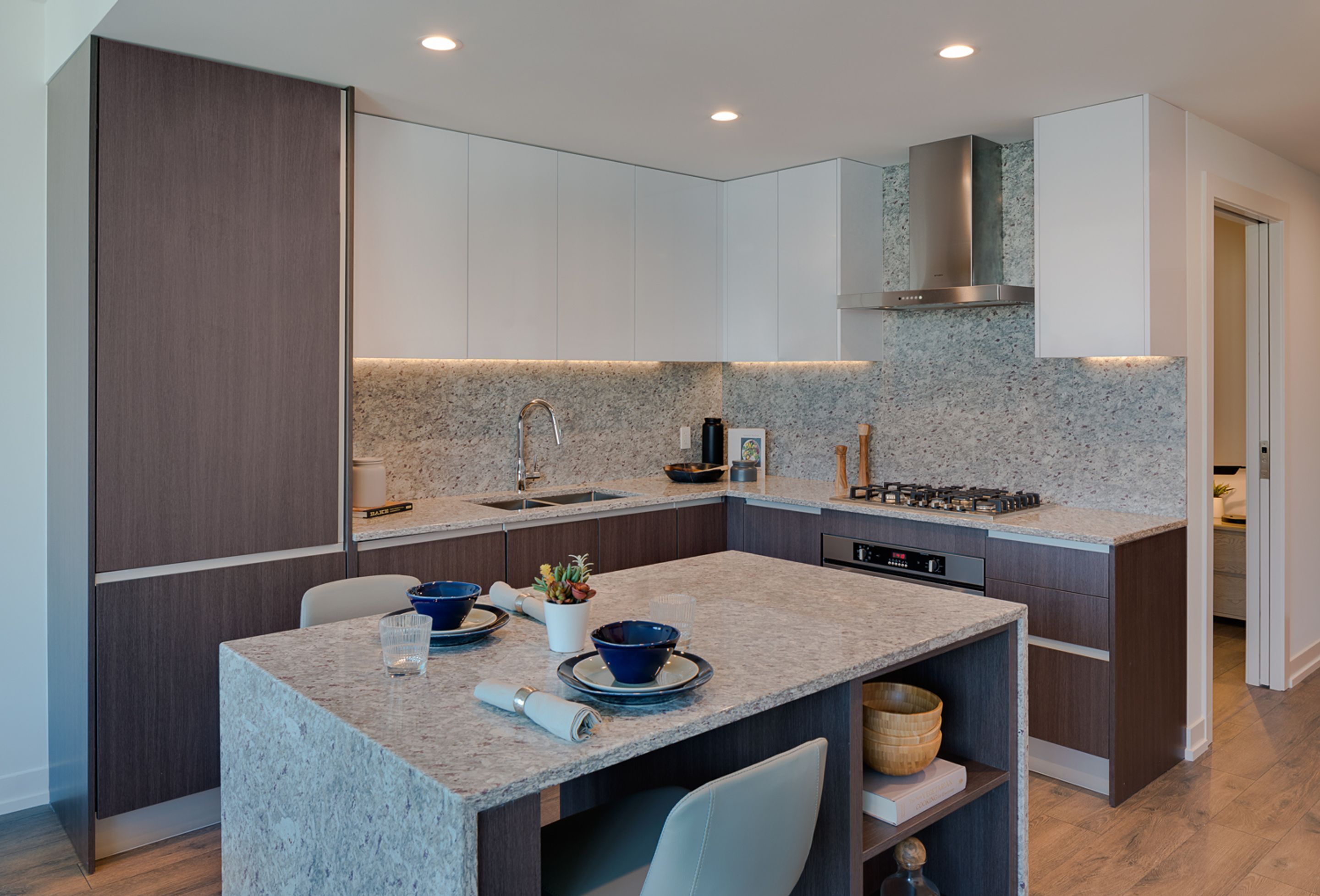 A modern kitchen with granite countertops, stainless steel appliances, and a central island with seating.