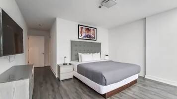 Et moderne hotelværelse med en stor seng, et fladskærms-tv, et natbord og et billede på væggen.