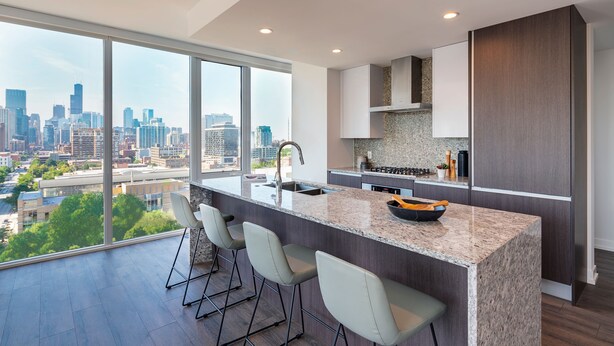 A modern kitchen with a large island, bar stools, and a city view.