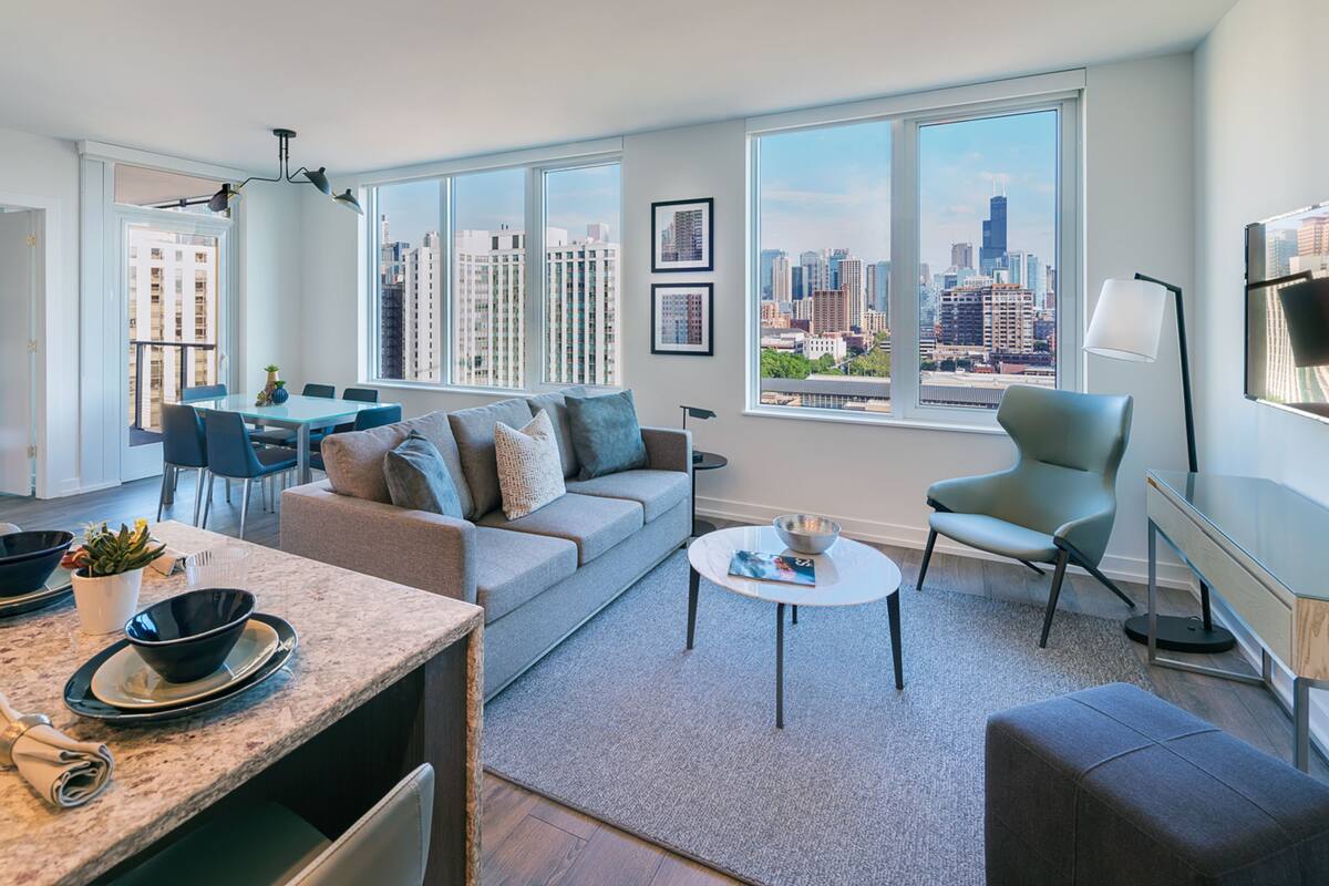 A modern living room with a city view, a dining area, and a kitchen.
