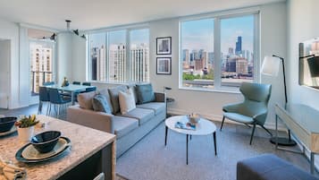 A modern living room with a city view, a dining area, and a kitchen.