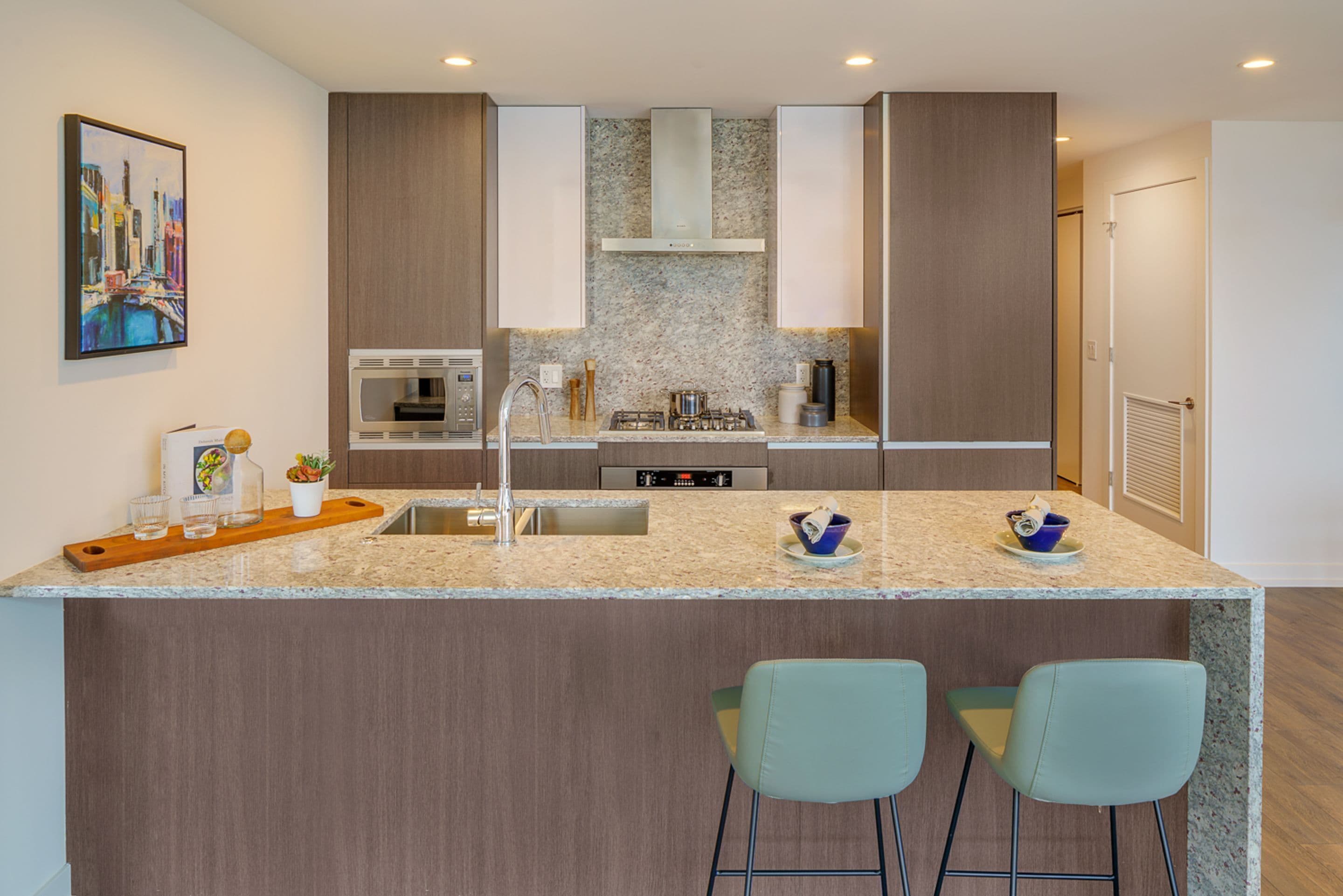 A modern kitchen with granite countertops, stainless steel appliances, and a central island with bar stools.