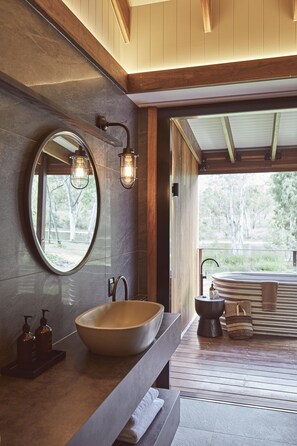 A modern bathroom with a large oval sink, a mirror, and two wall-mounted lights. - Mt Mulligan Lodge (Mount Mulligan)