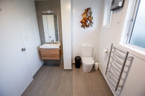 A modern bathroom with a wooden vanity, a toilet, and a towel rack. - Sydney Street Apartments (Queenstown)